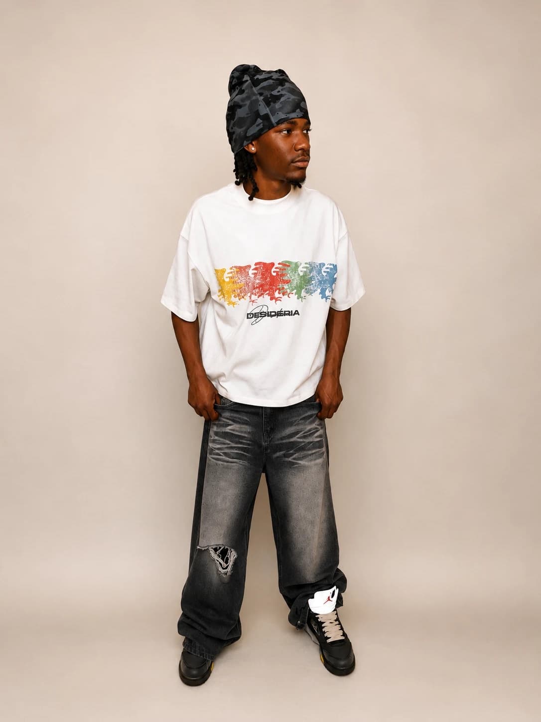 Dispersion tee in studio with a camo beanie and washed black denim