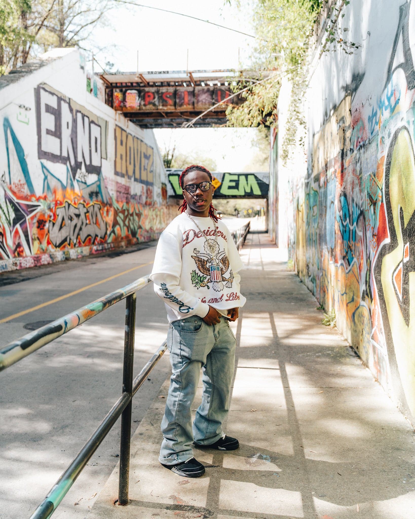 Model in the Life & Liberty double sleeve standing in a graffiti-covered underpass