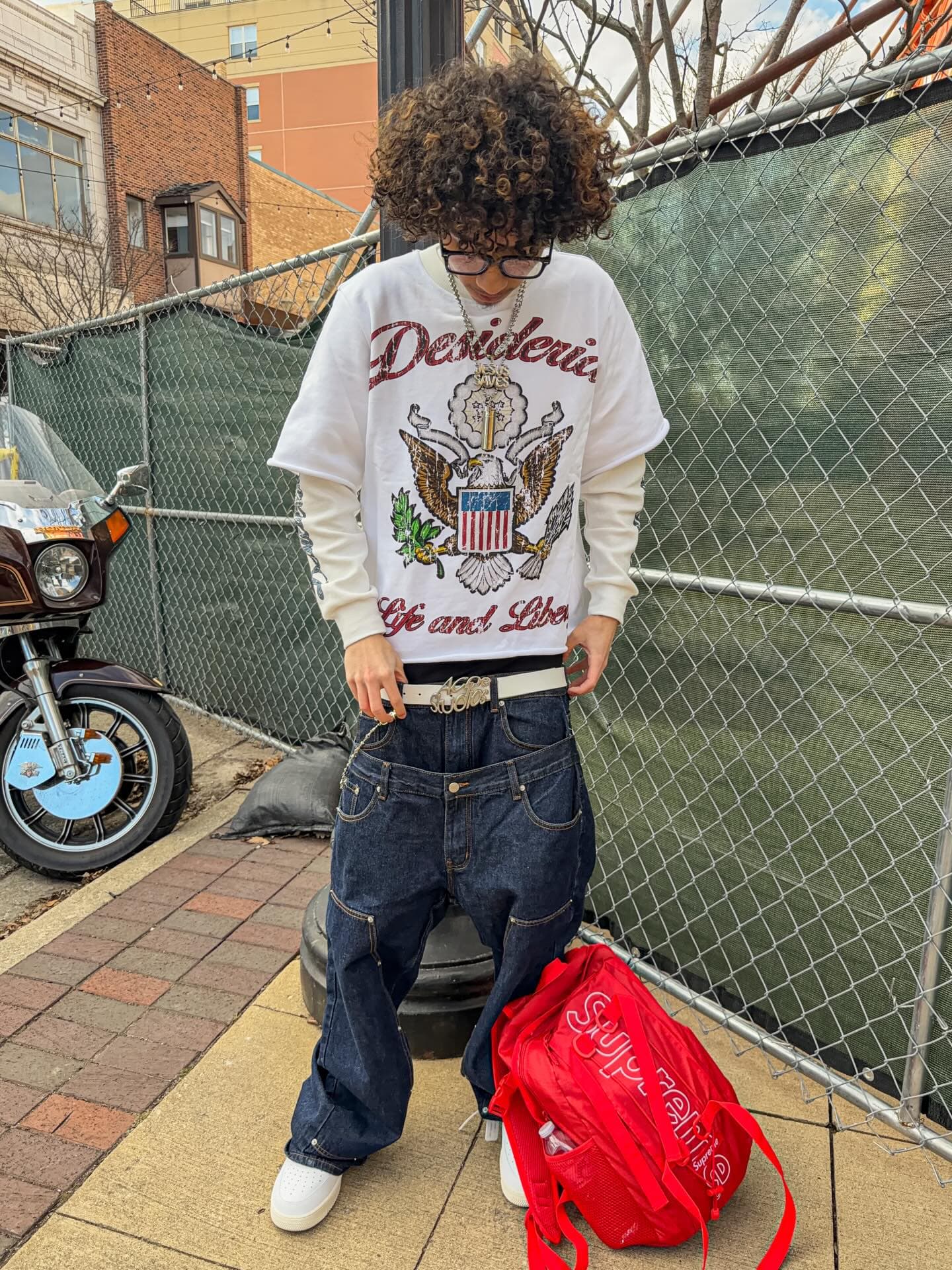 Double sleeve at a chain-link fence, vintage motorcycle behind